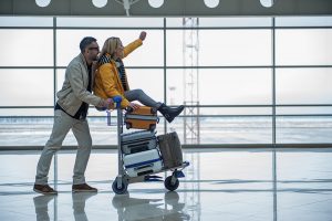 couple on luggage cart in airport